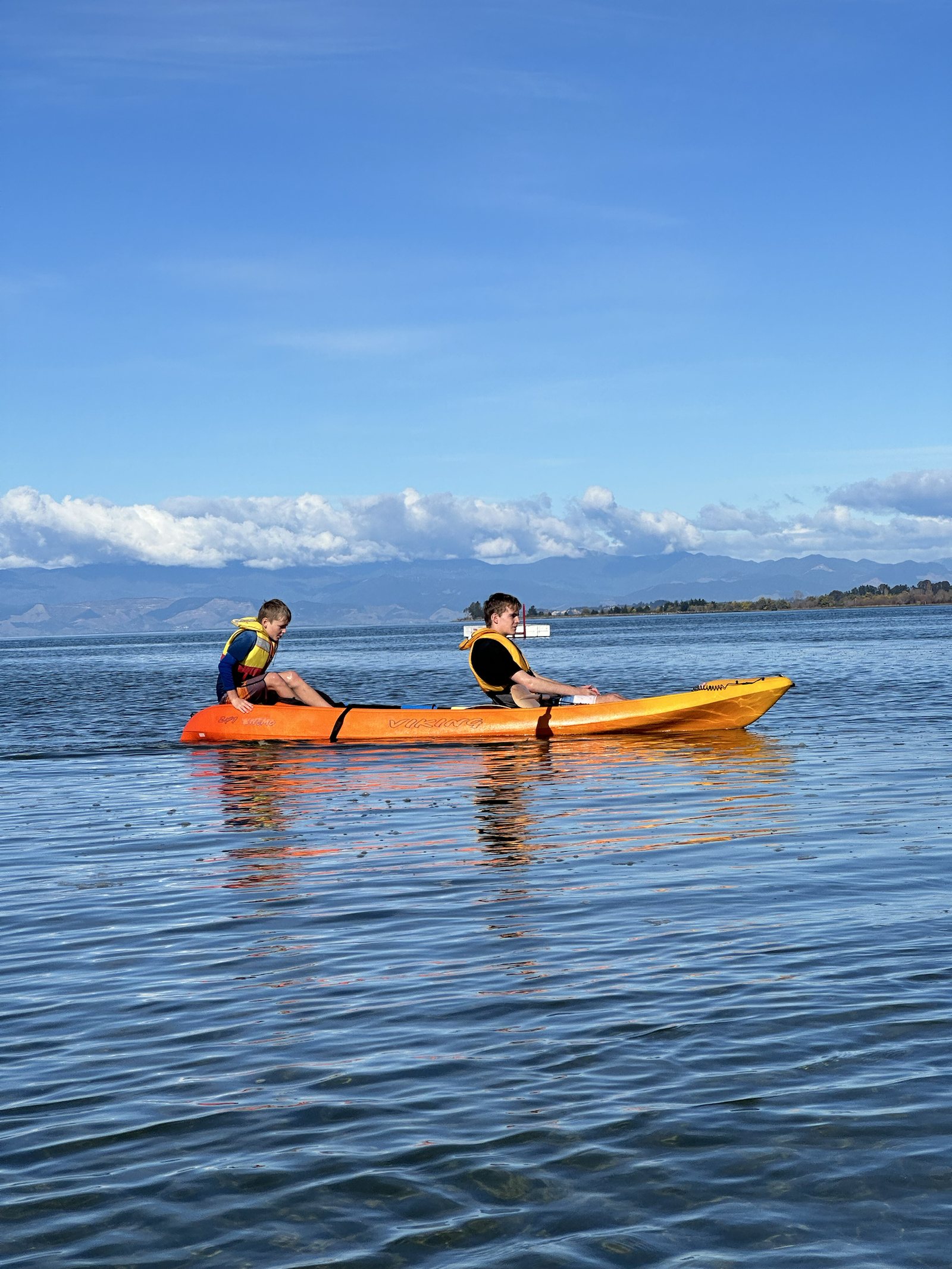 Two people kayaking on calm blue water